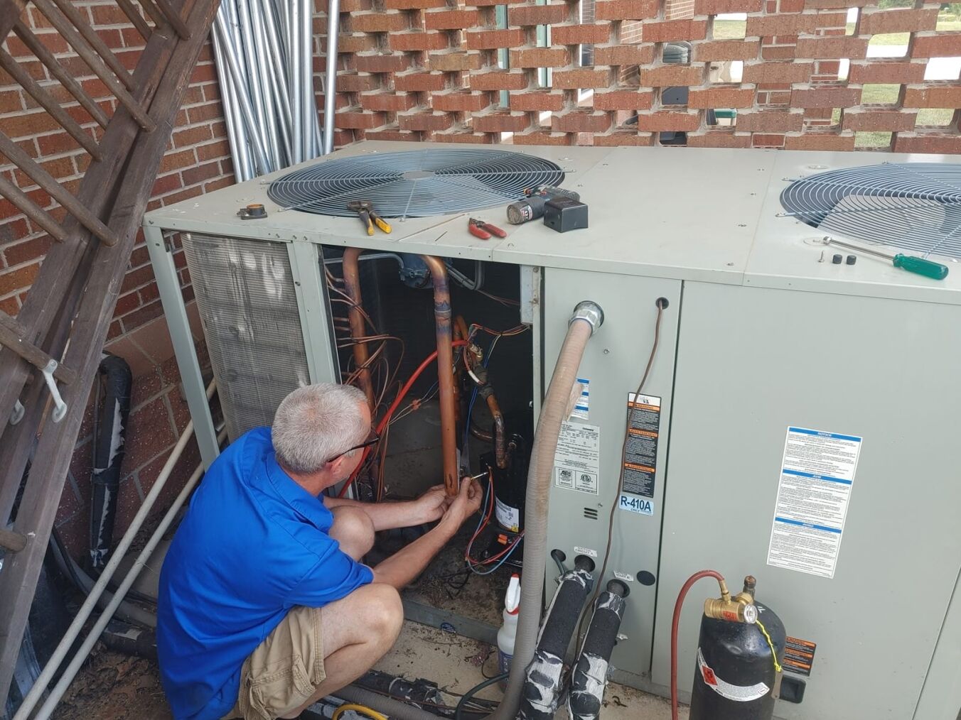 A technician repairing an outdoor air conditioning unit.