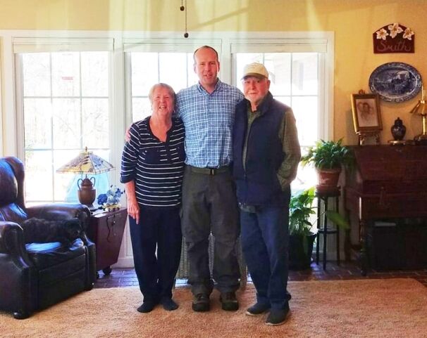 Three individuals posing for a photo in a well-lit living room.