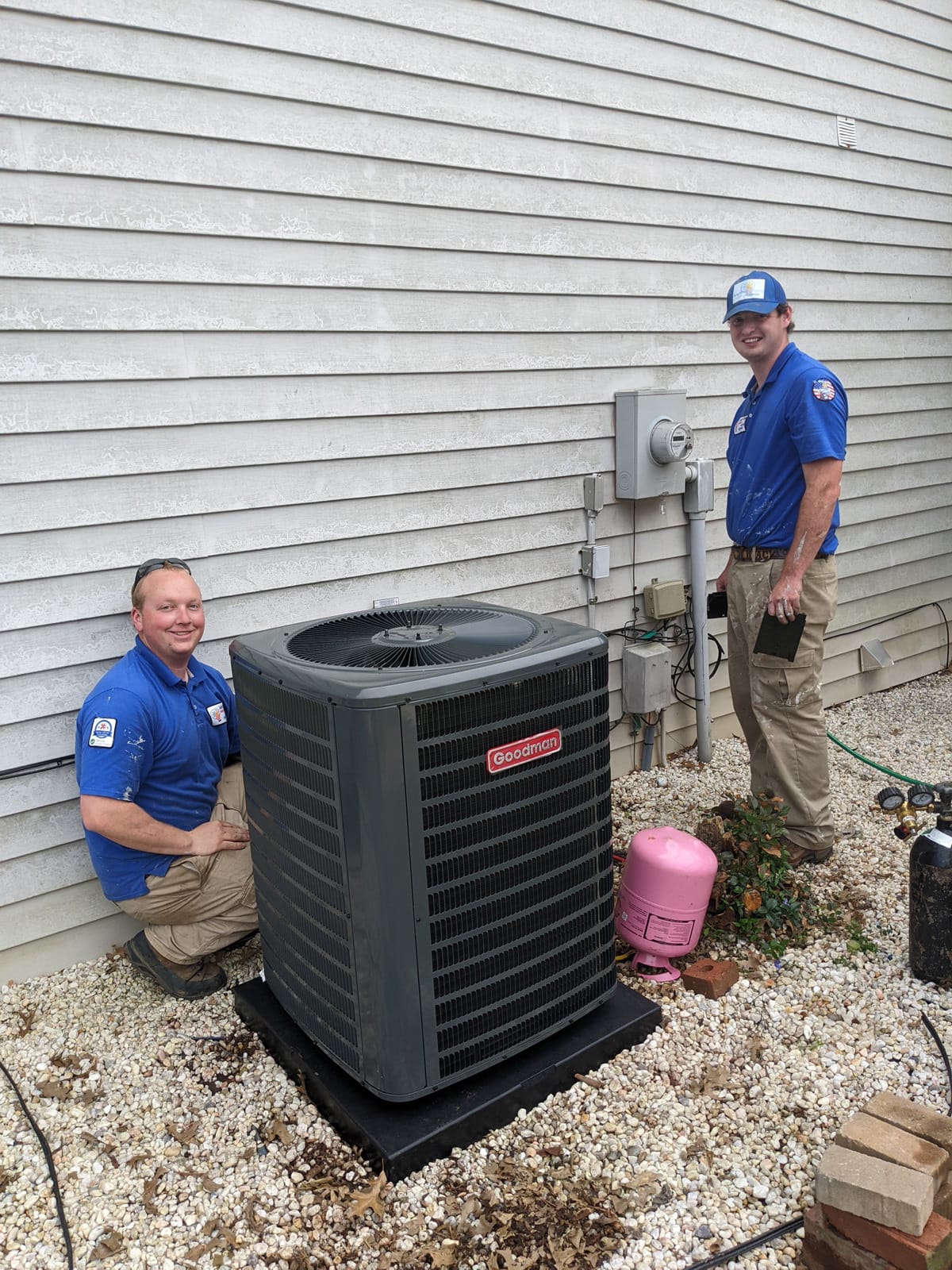 Two technicians servicing an outdoor air conditioning unit.