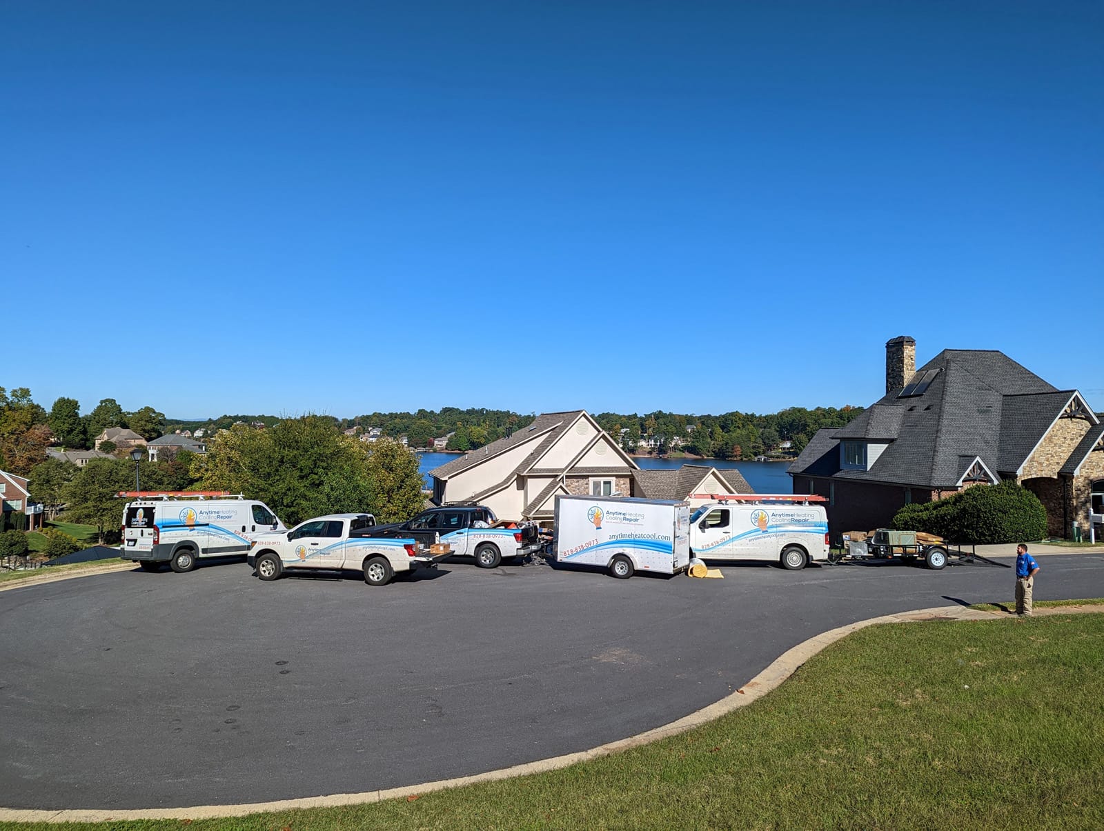 HVAC service vehicles parked in front of suburban homes on a clear day.