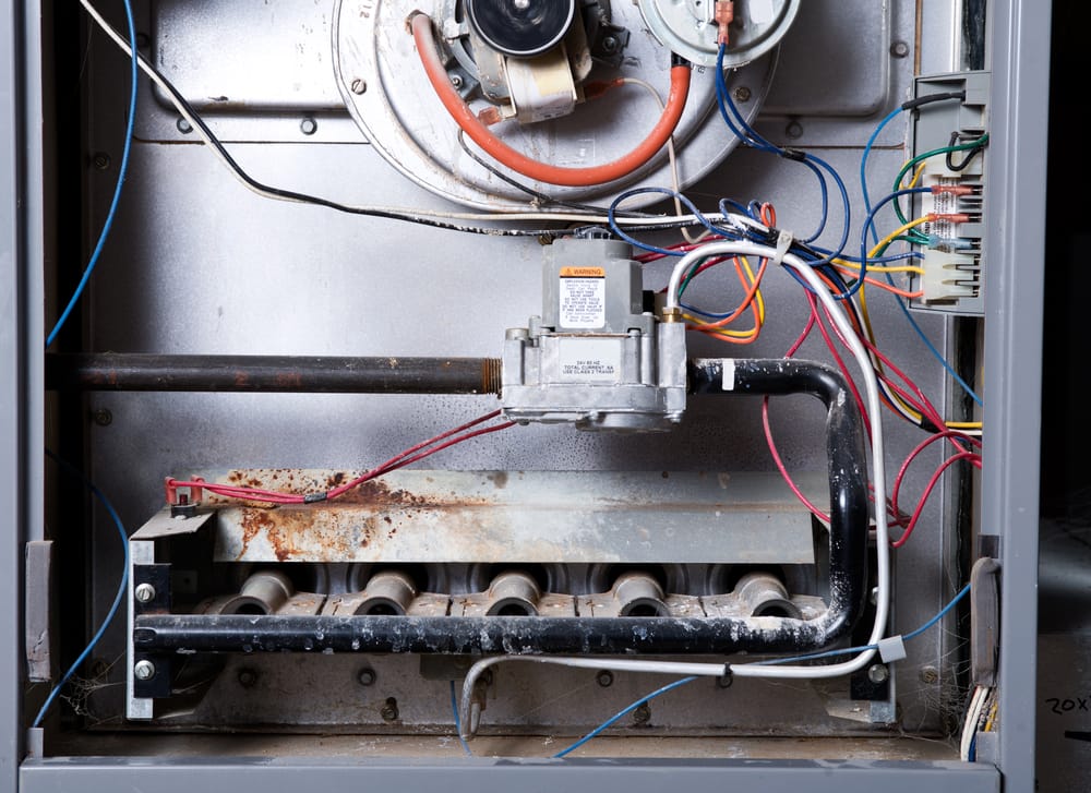Interior view of a gas furnace showing components and signs of rust,.