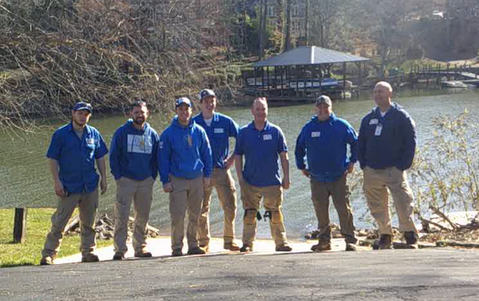 Anytime Heating Cooling Repair Tem posing for a photo outdoors near a body of water with trees and a boat dock in the background