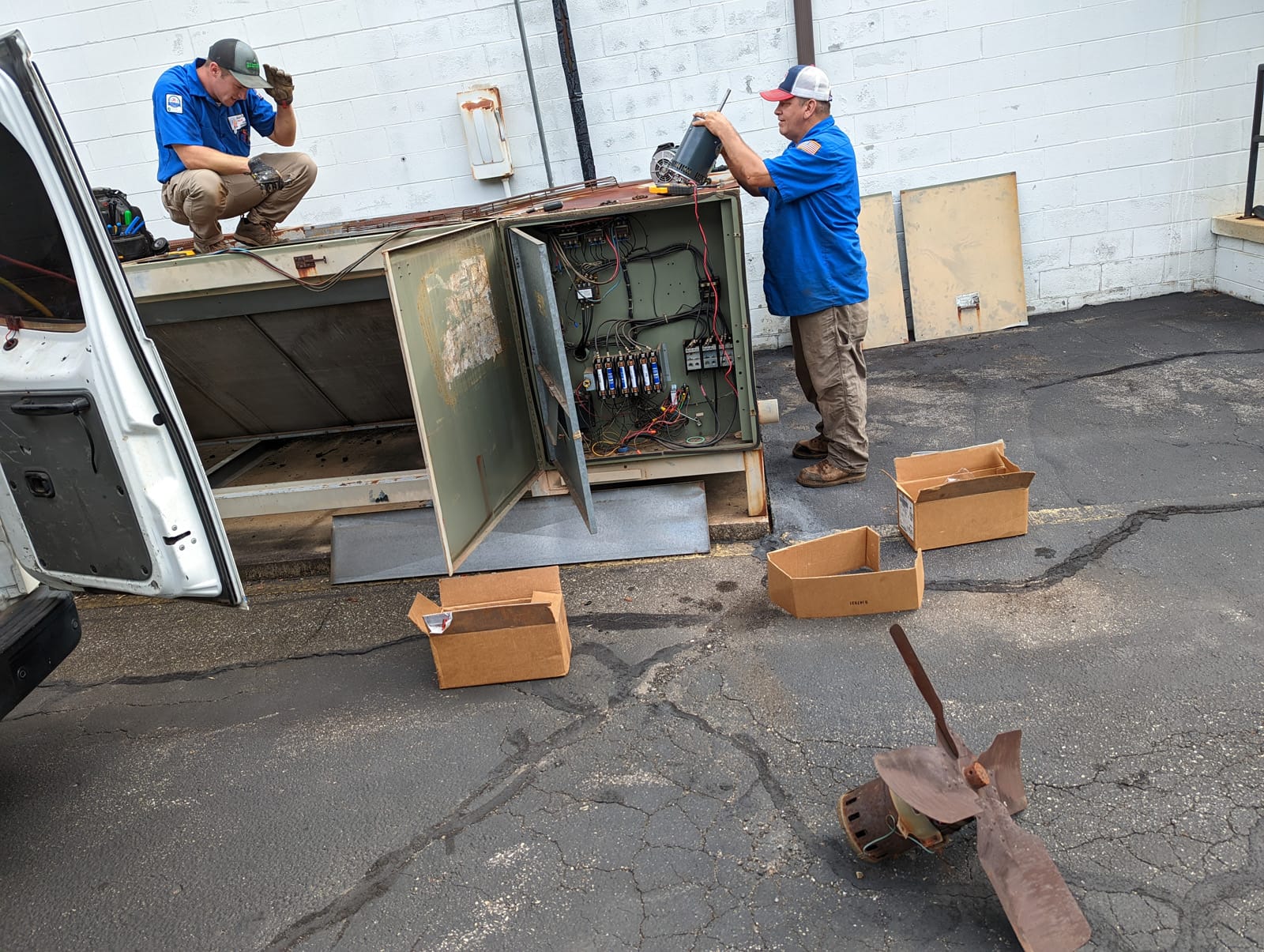 Two HVAC technicians working on an electrical panel.