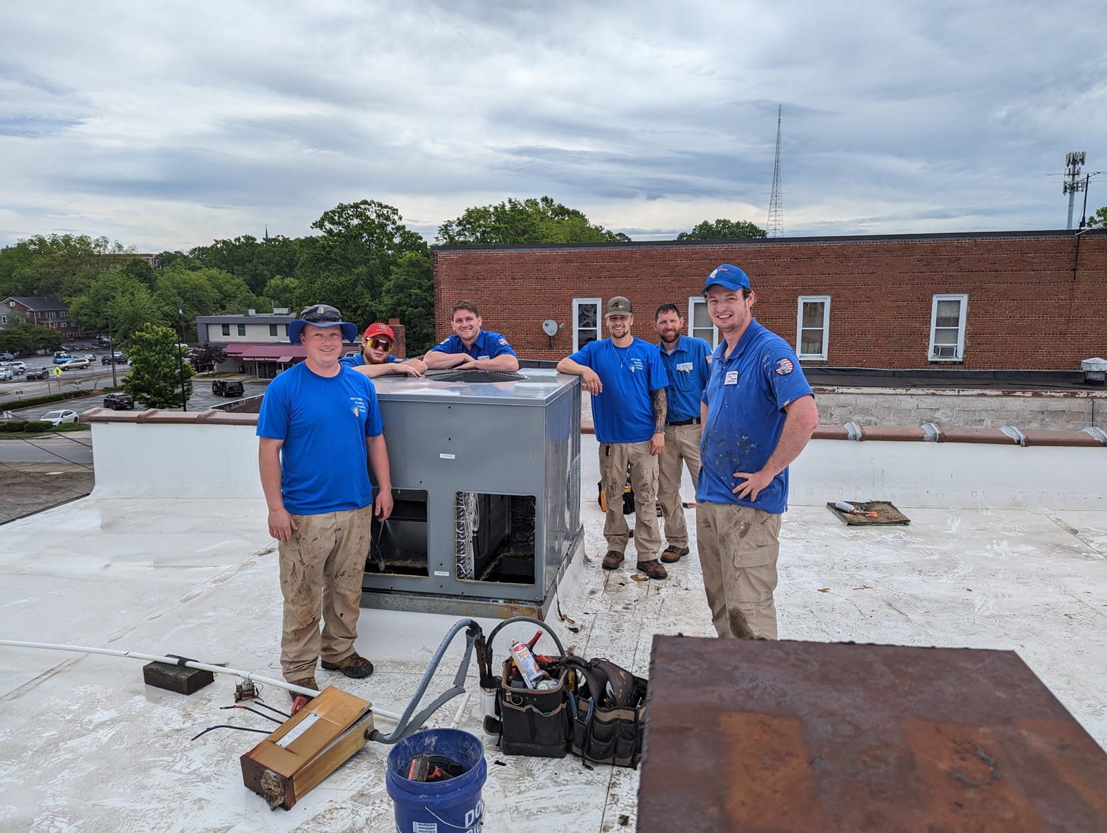 A team of HVAC technicians posing with new equipment on a rooftop, showcasing the benefits of HVAC systems for businesses in Hickory, NC.
