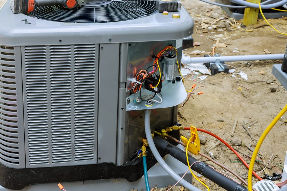 Air conditioning unit undergoing AC repair in Newton, NC, with its internal components and wiring exposed to fix weird noises.