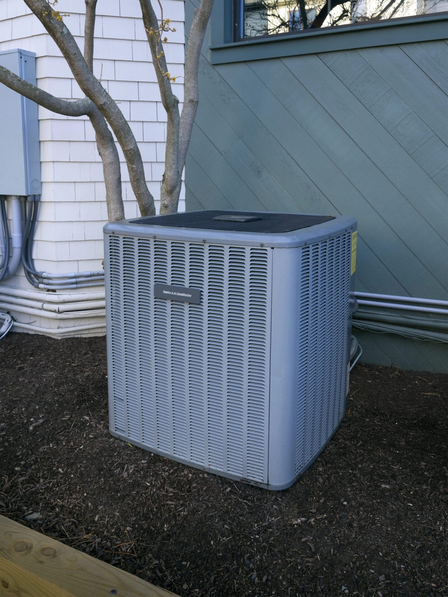 Outdoor central air conditioning unit beside a house.