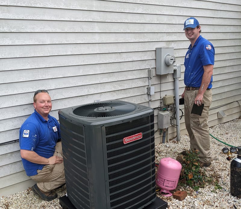 Two hvac technicians servicing an outdoor air conditioning unit in Catawba NC